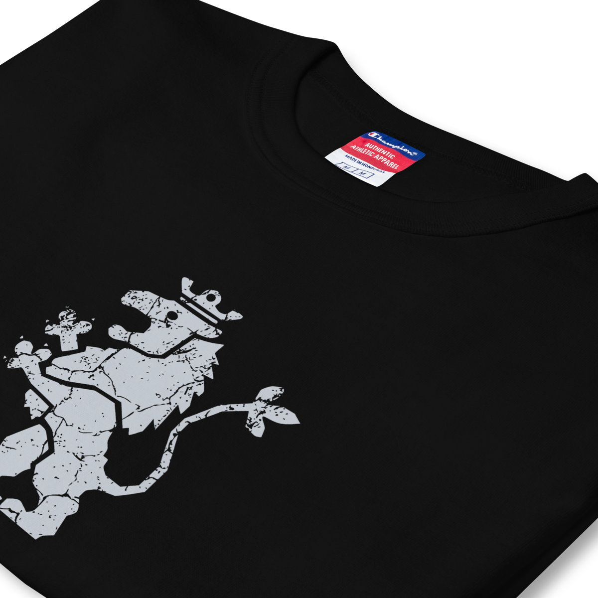 Folded side profile of black heavyweight, 100% cotton luxury Champion© t-shirt featuring aged lion emblem and text "EST. 1984" indicating the year the faction was first introduced to the brick universe. Item is a BRKDrip Heritage Collection luxury shirt with a vintage castle building block aesthetic.